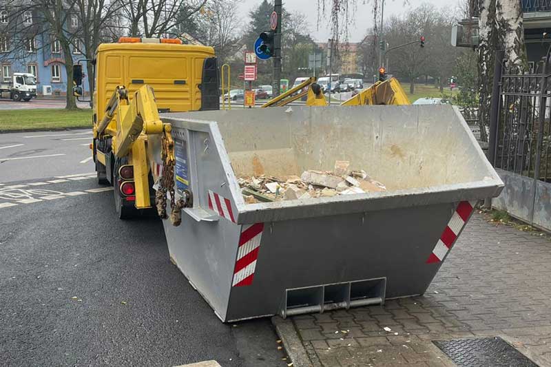 LKW von ARM Containerdienst nimmt gefüllten Abfallcontainer auf