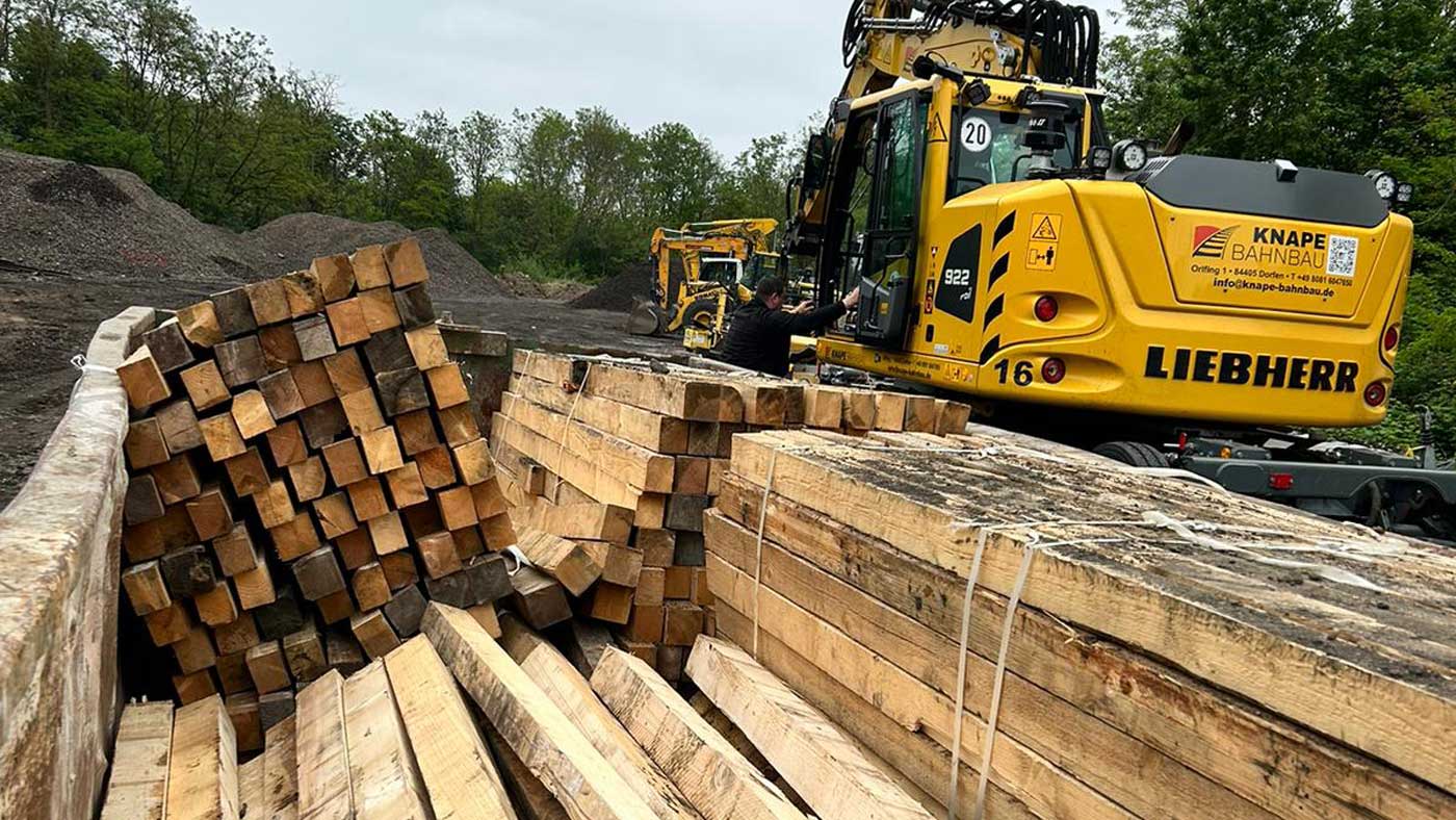 Gleisabschnitt in Frankfurt mit frisch verlegten Holzschwellen, umgeben von Bäumen und der städtischen Kulisse.