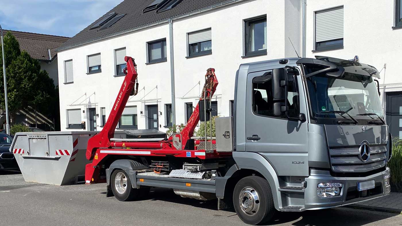 Abfallentsorgung in Aktion: Arbeiter von Containerdienst Frankfurt beladen einen Mischmüll-Container