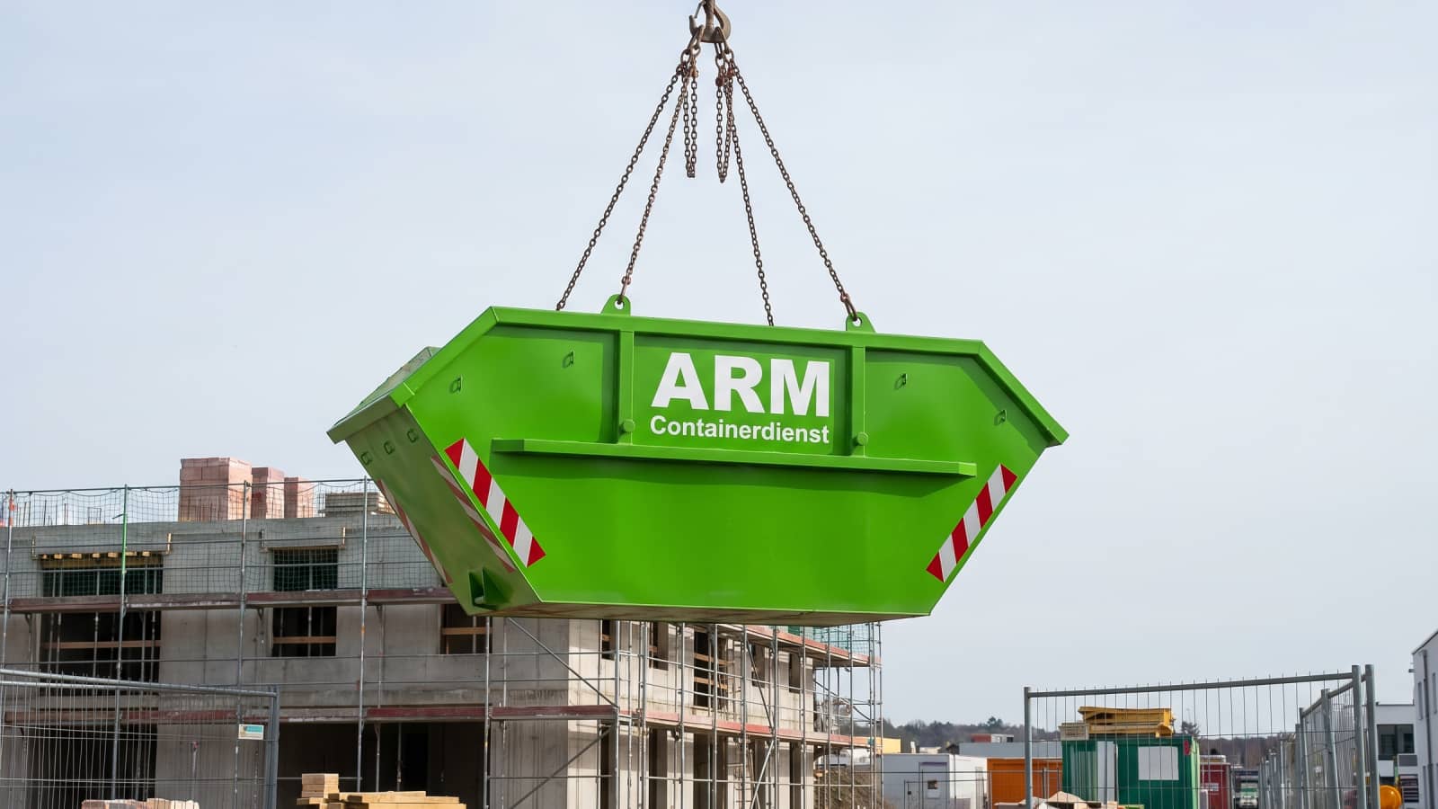 Grüner ARM-Containerdienst-Absetzcontainer am Kranhaken über einer Baustelle Grüner ARM-Containerdienst-Absetzcontainer am Kranhaken über einer Baustelle