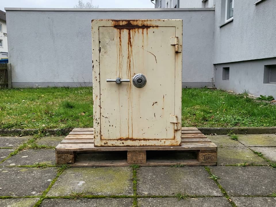 Alter Panzerschrank mit Rostspuren steht abholbereit auf einer Europalette im Hof Alter Panzerschrank mit Rostspuren steht abholbereit auf einer Europalette im Hof
